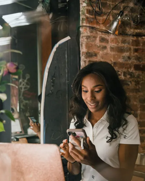 A business owner checking her phone with a laptop open